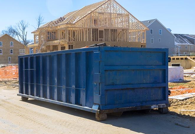 a construction site with a large blue waste dumpster in the background